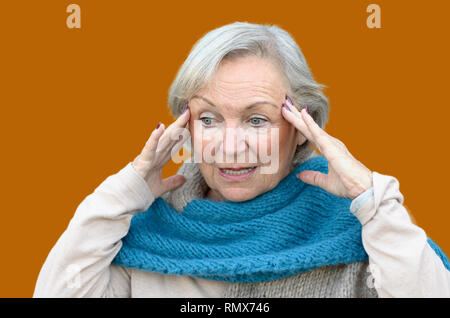 Confusi e disorientati senior lady tenendo le sue mani per i suoi templi come si guarda a parte, concettuale di insorgenza di demenza o morbo di Alzheimer Foto Stock