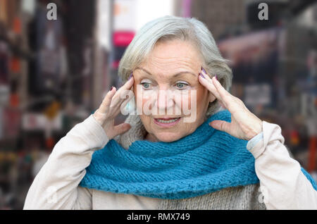 Confusi e disorientati senior lady tenendo le sue mani per i suoi templi come si guarda a parte, concettuale di insorgenza di demenza o morbo di Alzheimer Foto Stock