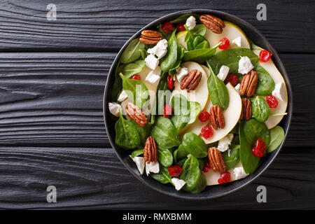 Dietetici di materie Insalata di pere, gli spinaci, le noci pecan, formaggio di capra e le ciliegie secche close-up su una piastra sul tavolo. parte superiore orizzontale vista da sopra Foto Stock