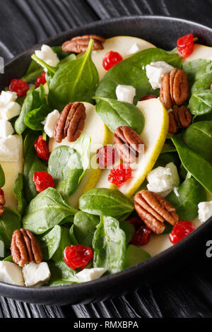 Dietetici di materie Insalata di pere, gli spinaci, le noci pecan, formaggio di capra e le ciliegie secche close-up su una piastra sul piano verticale. Foto Stock