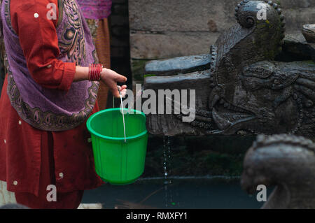 Non identificato donna Nepalese raccoglie acqua fresca in un vicino tempio di Patan Square, Kathmandu, Nepal. Foto Stock