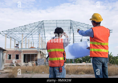 Due ingegneri e lavoratore cerca blueprint al sito in costruzione Foto Stock
