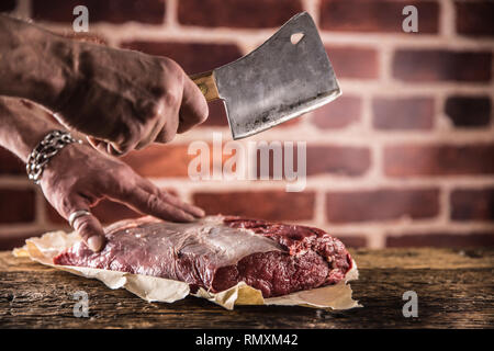 Butcher man mano il taglio di materie bistecca in macelleria. Foto Stock