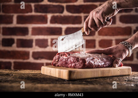 Butcher man mano il taglio di materie bistecca in macelleria. Foto Stock