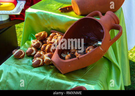 Pane appena sfornato panini con crostini di crosta croccante giacciono su una rotta Brown Jug. Il concetto di cottura per una cucina sana e gustosa. Foto Stock