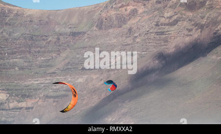 Persone che fanno il kite surf sulla spiaggia di Famara a Lanzarote, Isole Canarie Foto Stock