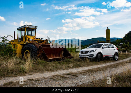 Auto Kia Sportage 2.0 Picanto 1.1 CRDI AWD o 4x4, colore bianco, parcheggiata sul prato accanto alla vecchia bulldozer giallo. Foto Stock