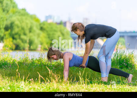 Un allenatore esperto le pratiche yoga su base individuale, sport all'aperto nel parco Foto Stock