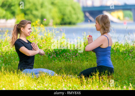 Coppia 40 anno vecchia donna le pratiche yoga con un allenatore esperto in un parco estivo Foto Stock