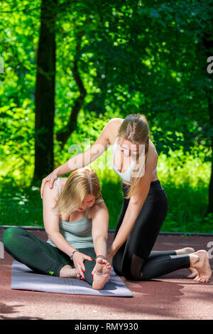 Le donne nel parco durante lo yoga, stretching esercizio Foto Stock