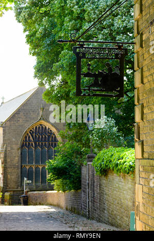 Close-up di lamiera nera segno appesa sul muro esterno di Bronte Parsonage Museum Brontes (home) & chiesa al di là - Haworth, nello Yorkshire, Inghilterra, Regno Unito. Foto Stock