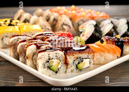 California roll vicino. Gustosi piatti sushi riempito con anguilla affumicata, avocado e crema di formaggio, unagi salsa topping. Uramaki sushi set. Foto Stock