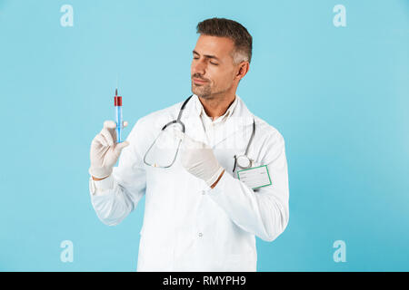Ritratto di coppia medico con stetoscopio in guanti tenendo la siringa in piedi isolato su sfondo blu Foto Stock