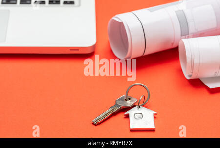 Immobili residenziali, la costruzione di alloggi. Chiave di casa e progetto blueprint sul colore arancione, spazio di copia Foto Stock