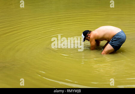 Uomo di raccolta lumache di allevamento in stagno Foto Stock