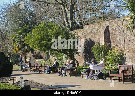 Persone godetevi il sole in una giornata invernale e nella zona londinese di Holland Park giardini di Kensington, una delle città più ricche aree. Foto Stock