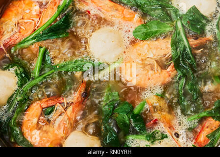 Close-up di una calda zuppa di pot pasto con gamberetti, vegetali di foglie e polpette di pesce in un brodo simmering, visto nelle Filippine Foto Stock