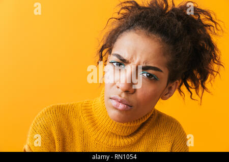 Sconvolto giovane donna africana che indossa un maglione in piedi isolato su sfondo giallo Foto Stock