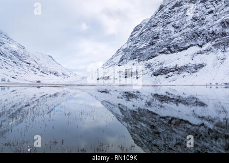 Snowy riflessioni in Loch Achtriochtan, Glencoe, Highlands scozzesi, Scotland Regno Unito nel gennaio Foto Stock