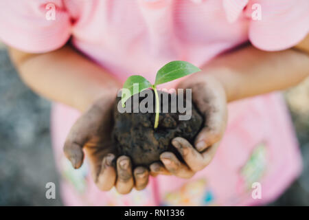 Carino kid di piantare un albero per aiutare a prevenire il riscaldamento globale o i cambiamenti climatici e salvare la terra. Foto per il concetto di Madre Terra giorno per incoraggiare Foto Stock