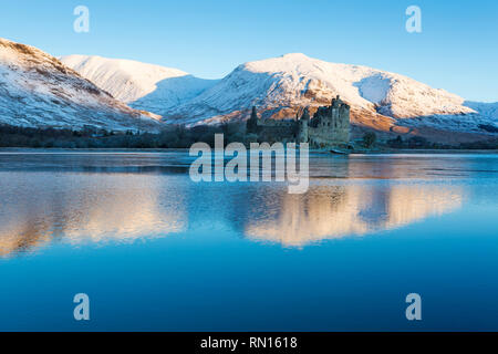 La mattina presto a Kilchurn Castle e Loch Awe, Argyll and Bute, Scozia in un freddo giorno di inverni con neve e sole solo illuminazione della montagna Foto Stock