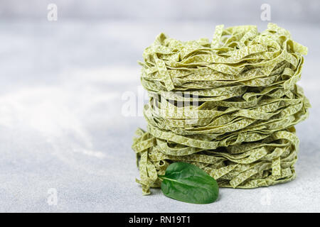 Materie casalingo italiano pasta verde tagliatelle con spinaci close-up. Asciugare gli spaghetti. Messa a fuoco selettiva, spazio di copia Foto Stock