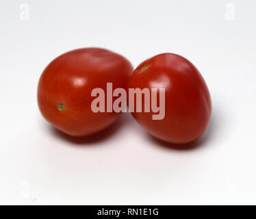 Sana e deliziosa pomodori ciliegia in un primo piano. Mature, pomodori rossi fotografata con obiettivo macro. Ci sono due pomodori in un tavolo bianco. Foto Stock