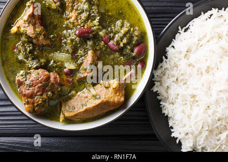 Autentica Ghormeh Sabzi piatto di stufato di agnello di carne con le erbe aromatiche e i fagioli in una terrina e riso sul tavolo. Parte superiore orizzontale vista da sopra Foto Stock