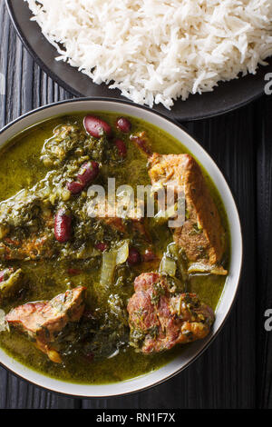 Autentica Ghormeh Sabzi piatto di stufato di agnello di carne con le erbe aromatiche e i fagioli in una terrina e riso sul tavolo. Verticale in alto vista da sopra Foto Stock