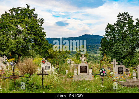 Transilvania, Romania - 1 agosto 2018: un vecchio cimitero del paese in un campo che si affaccia sulla catena dei Carpazi. Foto Stock