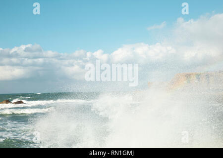 Un bel blu turchese grandi onde che si infrangono sulle la lente e il cielo nuvoloso come sfondo, spazio di copia Foto Stock