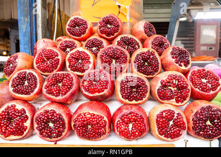 Pila di red succosa frutti di melograno, vicino, metà tagliate al mercato Carmel di Tel Aviv-Jaffa, Israele Foto Stock
