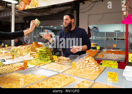 Tel Aviv, mercato Carmel, Israele - 28 dicembre 2018:un giovane uomo con barba tradizionali di vendita, Oriental Sweet dessert - baklava - al mercato Carmel Foto Stock