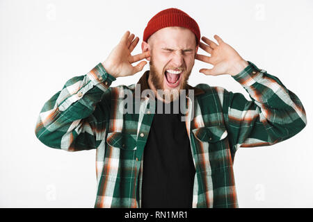 Immagine del sistema nervoso barbuto ragazzo indossa un cappello e plaid shirt urlando mentre in piedi isolato su sfondo bianco Foto Stock