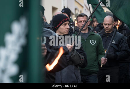 Fulda, Germania. Xvi Feb, 2019. Con le torce nelle loro mani, dimostranti dall'estremista di destra mini-party 'Der dritte Weg a piedi attraverso il centro della città durante il mese di marzo per commemorare il bombardamento di Dresda da truppe alleate nella Seconda Guerra Mondiale. La polizia ci sono con un grande contingente per impedire un incontro con contro i dimostranti. Credito: Boris Roessler/dpa/Alamy Live News Foto Stock