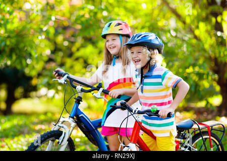 Ragazzi in bici nel Parco. Ai bambini di andare a scuola sicuro che indossa caschi da bicicletta. Piccolo Ragazzo e ragazza in bicicletta sulla soleggiata giornata estiva. Active outdoor sano sp Foto Stock