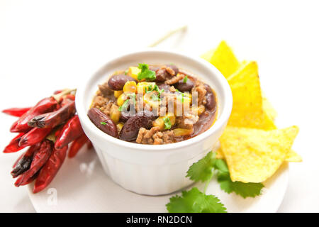 Chili con carne in un vaso di argilla su un bianco sfondo luminoso- piatto tradizionale della cucina messicana. Foto Stock