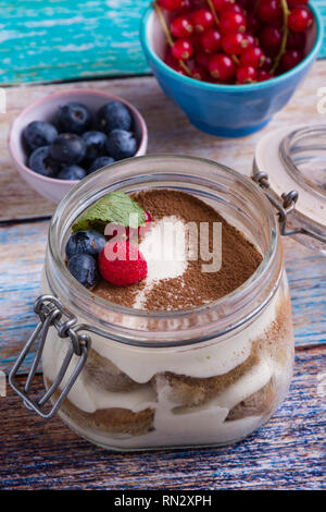 Gustosi dessert Tiramisu in un barattolo di vetro sulla tavola a colori Foto Stock