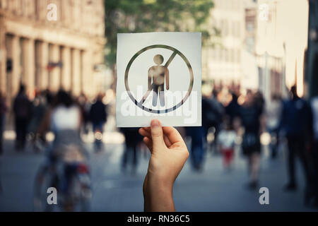 Il tasso di disoccupazione globale come mano che tiene un foglio di carta con la persona dipendente icona sopra una strada affollata dello sfondo. Problema sociale, mancanza di economica o Foto Stock