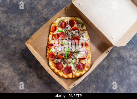 Pizza con diversi condimenti in scatola di consegna Foto Stock