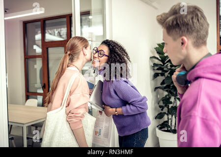 Curly afro-americano di studente a baciare la sua amica di guancia Foto Stock