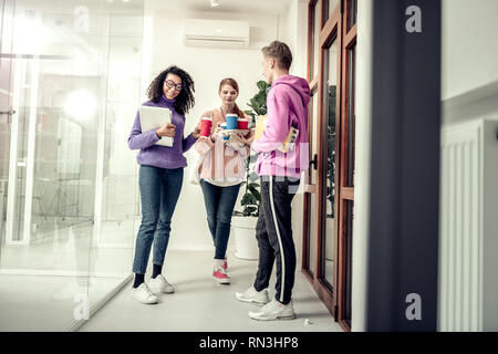 Tre eleganti studente a bere il caffè da asporto in università Foto Stock