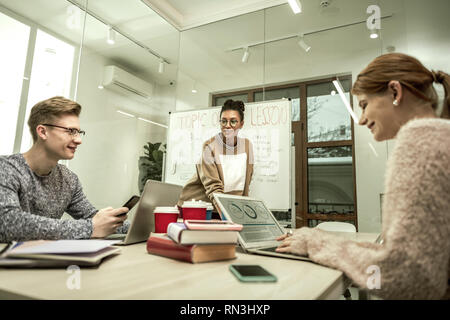 Gli studenti utilizzano i computer portatili durante la classe con il loro nuovo insegnante Foto Stock