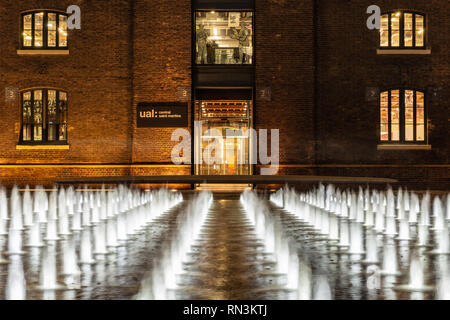 London, England, Regno Unito - 20 dicembre 2018: le fontane sono illuminate di notte in Piazza Grannary fuori Central Saint Martin's College dell'Università degli Foto Stock