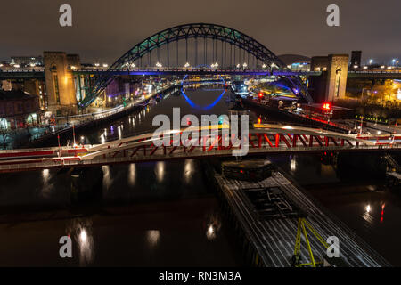 Newcastle, England, Regno Unito - 3 Febbraio 2019: la mitica Tyne Bridge e ponte girevole tra Newcastle e Gateshead sono illuminate di notte e riflessa in t Foto Stock