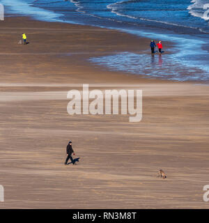 Tynemouth, England, Regno Unito - 4 Febbraio 2019: la gente a piedi i loro cani sulla spiaggia espansiva di Longsands Tynemouth su una soleggiata giornata invernale. Foto Stock