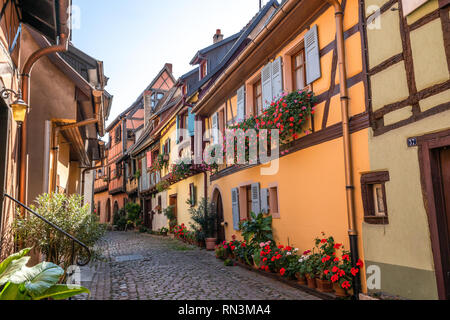 Strada di ciottoli in Alsace Francia villaggio con case colorate e fiori sulla giornata di sole. Foto Stock