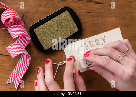 Le mani della donna che fa buon Natale etichetta Foto Stock