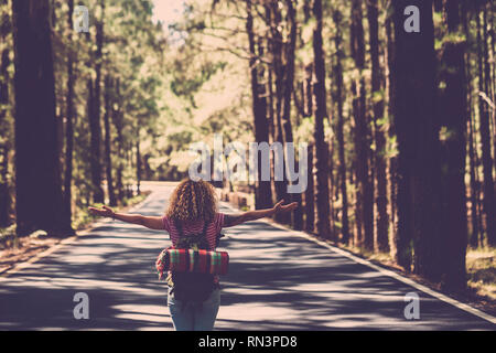 L'eternità e la soddisfazione del successo il concetto di vita con lonely girl curly hai rin medio della lunga strada nella foresta con le braccia aperte e zaino - emulazione penna ottica Foto Stock