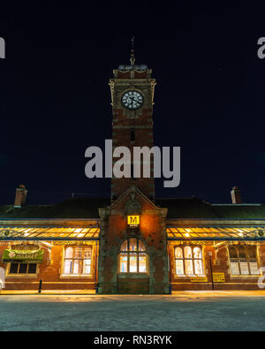 Whitley Bay, England, Regno Unito - 4 Febbraio 2019: gli ornati di architettura vittoriana esterno di Whitley Bay Station è illuminata di notte sul Tyne e Weir M Foto Stock